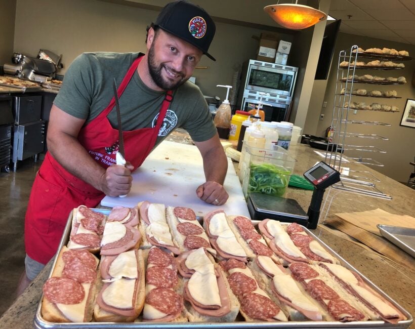 Pizza Factory Owner in front of sub sandwich tray