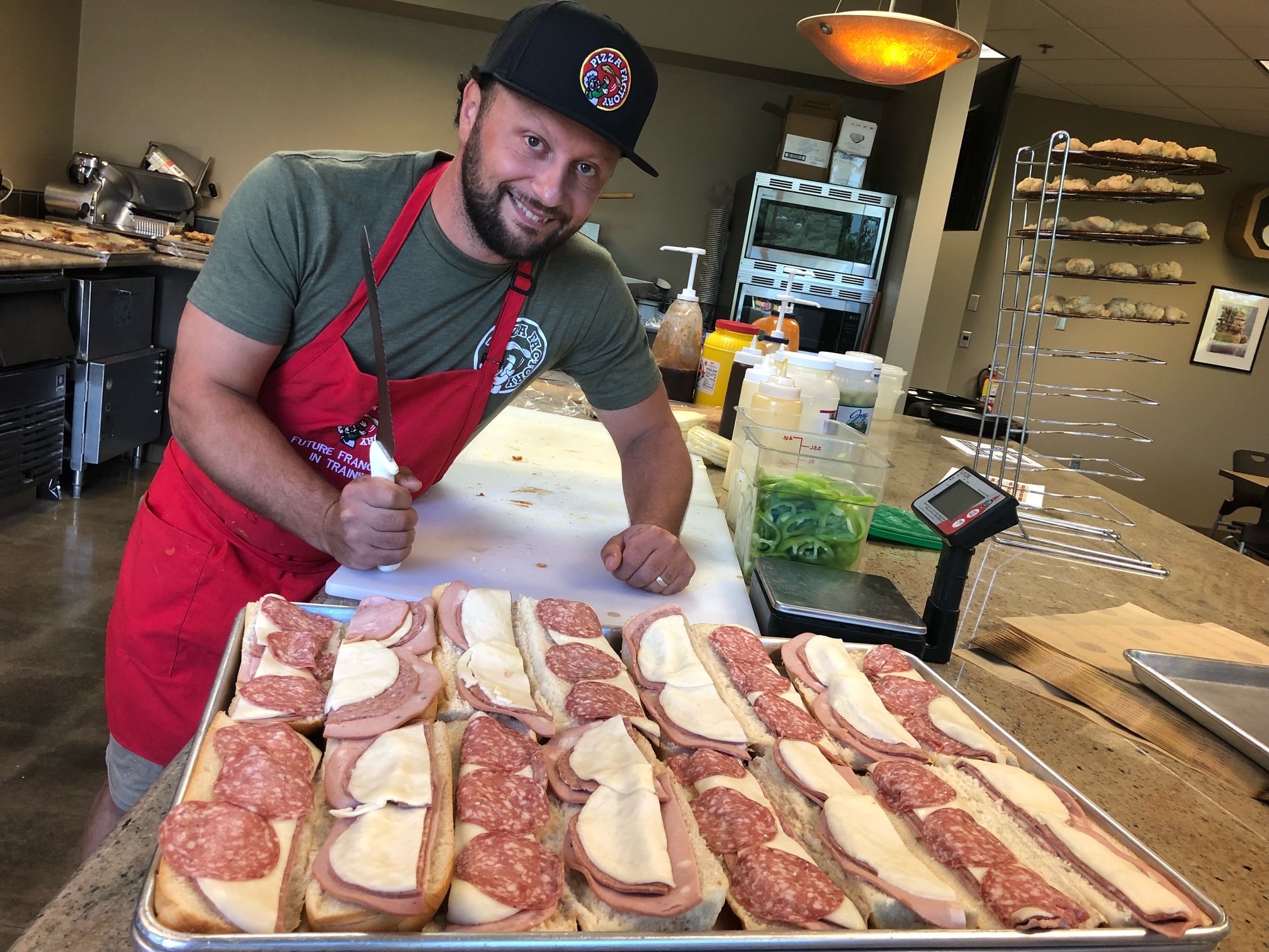 Pizza Factory Owner in front of sub sandwich tray