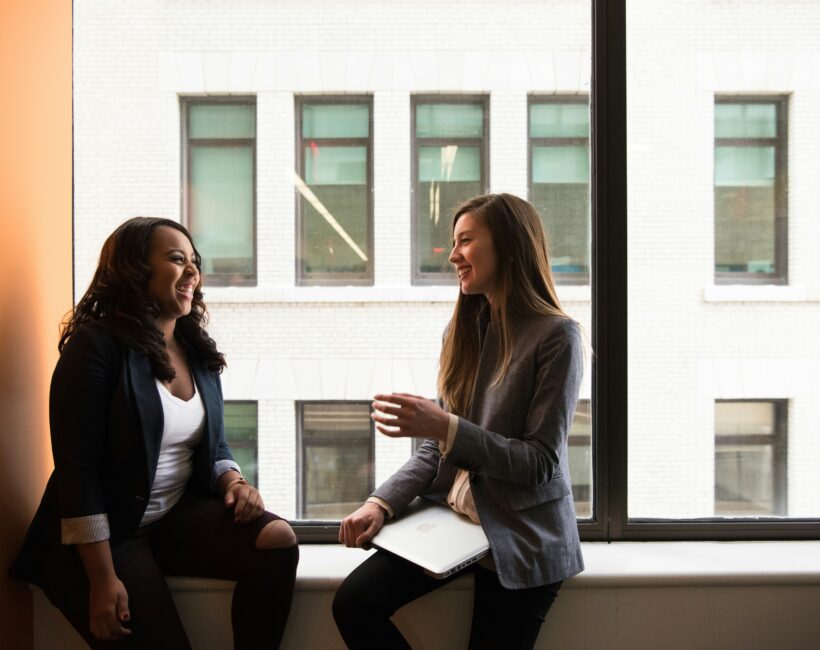 female-owned franchises - two women talking in front of. a window.