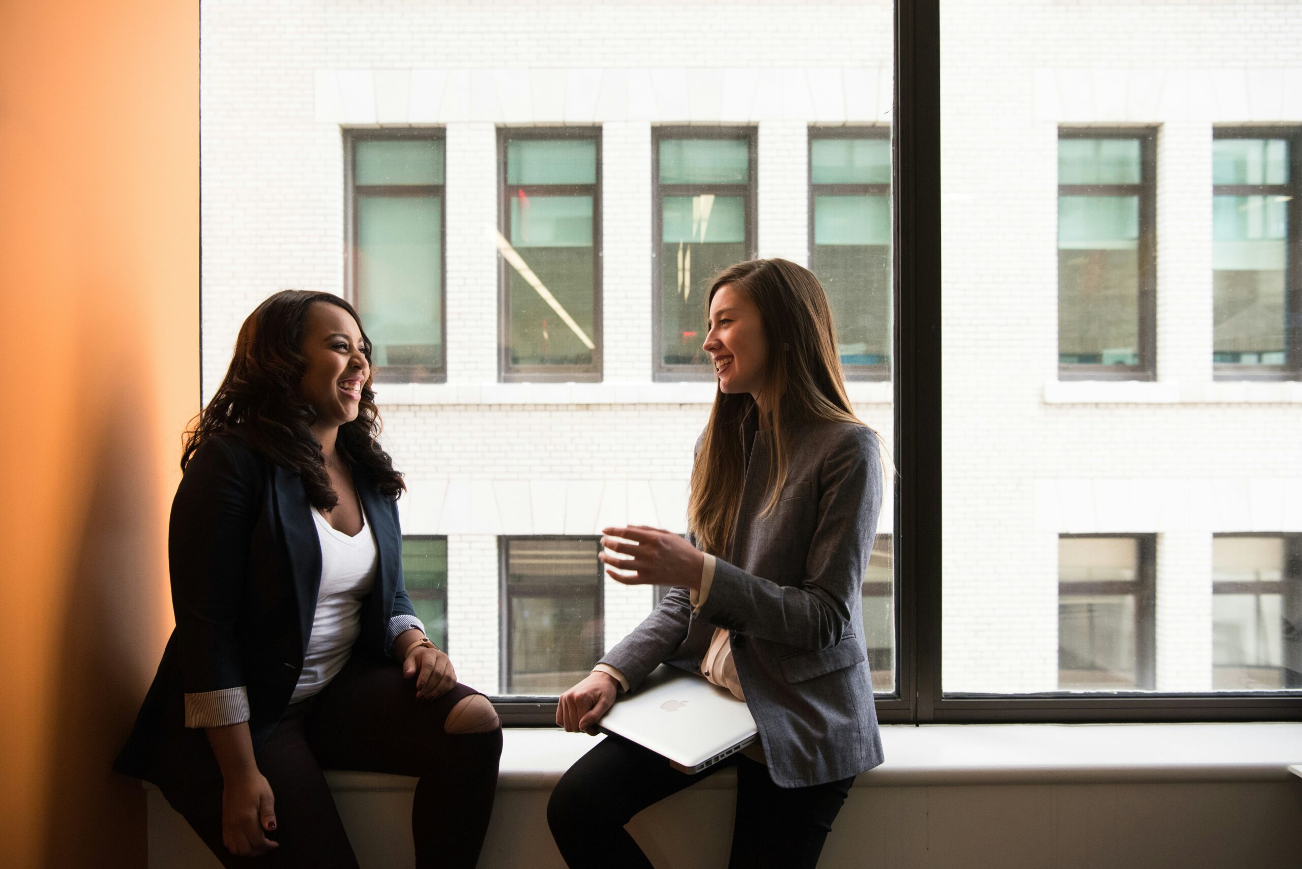 female-owned franchises - two women talking in front of. a window.