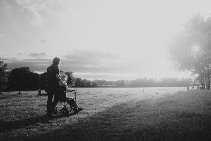 person pushing another in a wheelchair down a beautiful outdoor path.