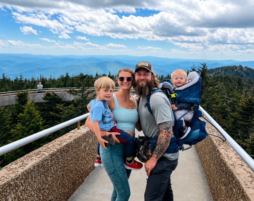 two parents with small children posing on a bridge traveling